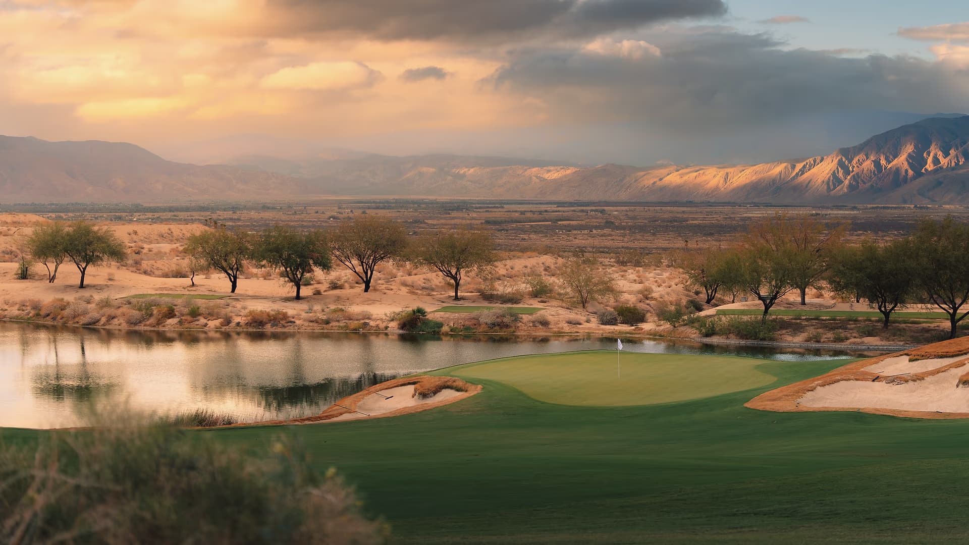 Golden hour at Rams Hill Golf Club, with a green and water set against the Borrego Springs desert and mountains.