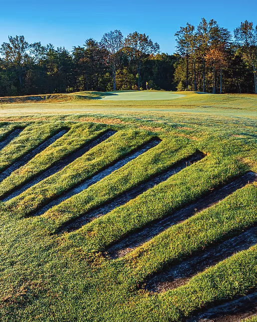 Stacked railroad-tie bunker faces stepping down a hillside at Cutalong, under autumn hardwoods.