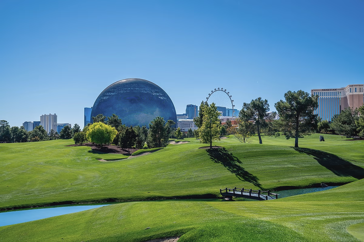 The Sphere rising above the fairway at Wynn Golf Club, with the High Roller wheel and the Las Vegas skyline beyond.
